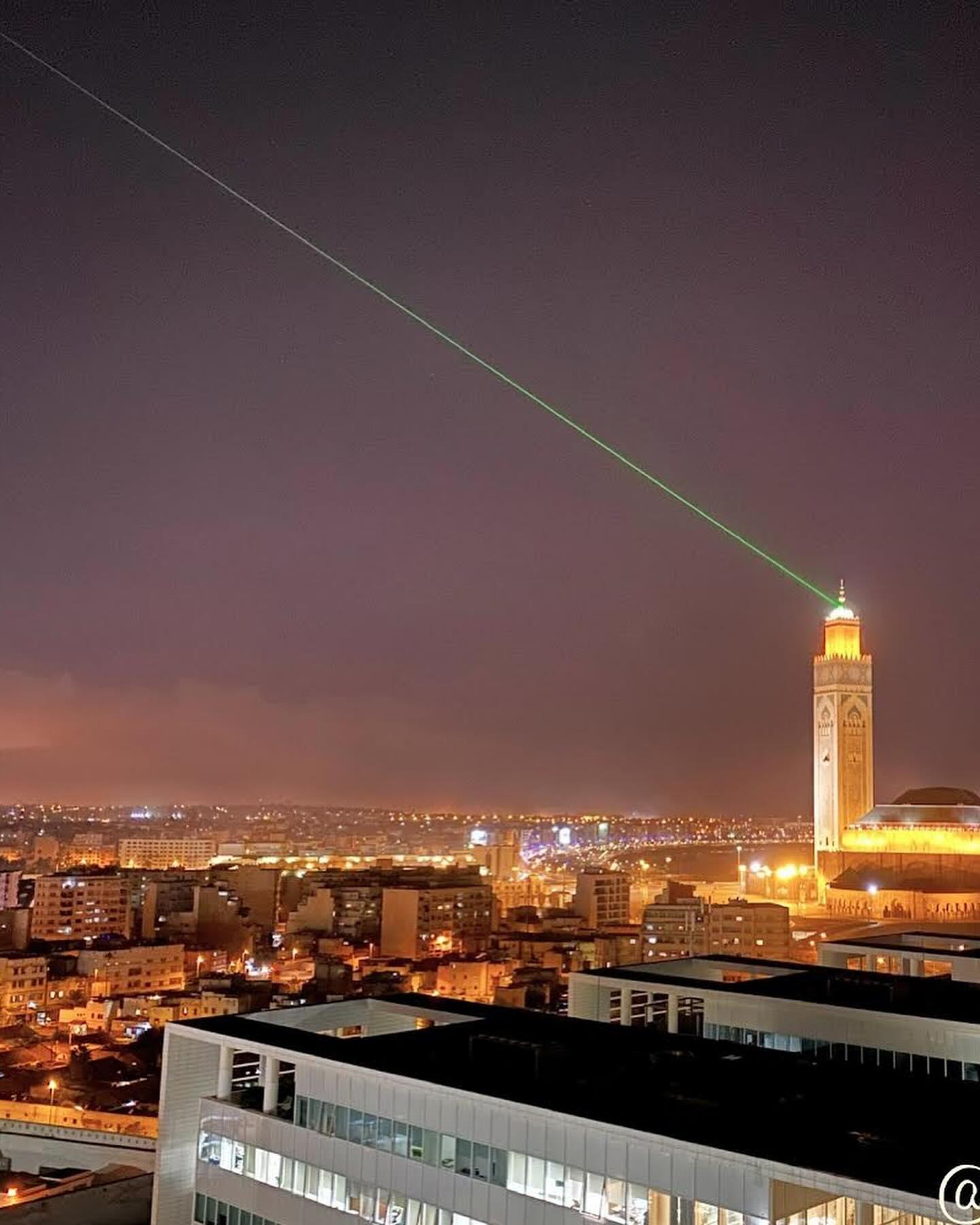 Hassan II Mosque lit at night against the Atlantic in Casablanca.