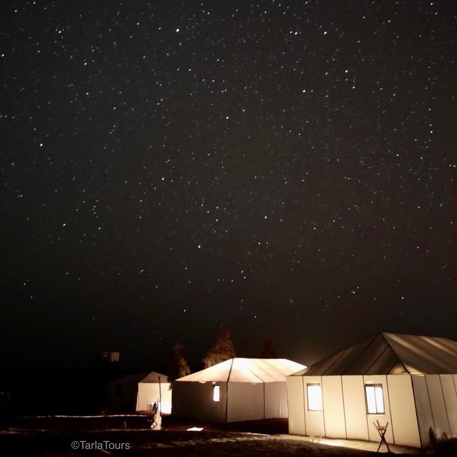 Luxury desert camp tents with the Erg Chebbi dunes rising behind.